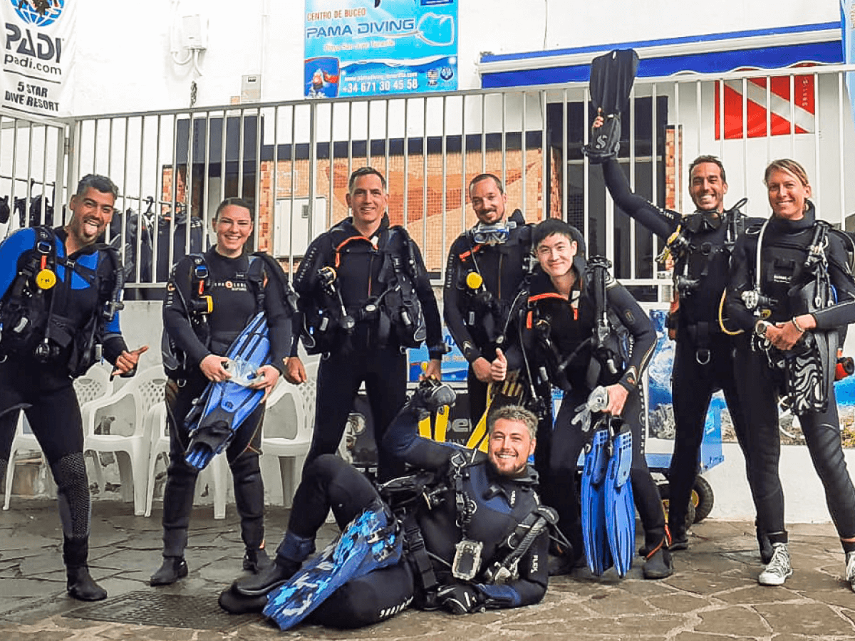 MUI team members and their diving instructors pose in scuba gear before a successful scuba diving lesson.